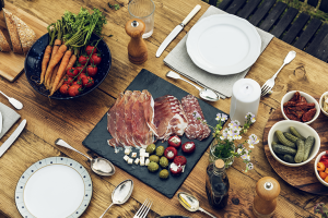 Mesa navideña elegante con Jamón Ibérico cortado y listo para servir, acompañado de vinos y decoraciones festivas.